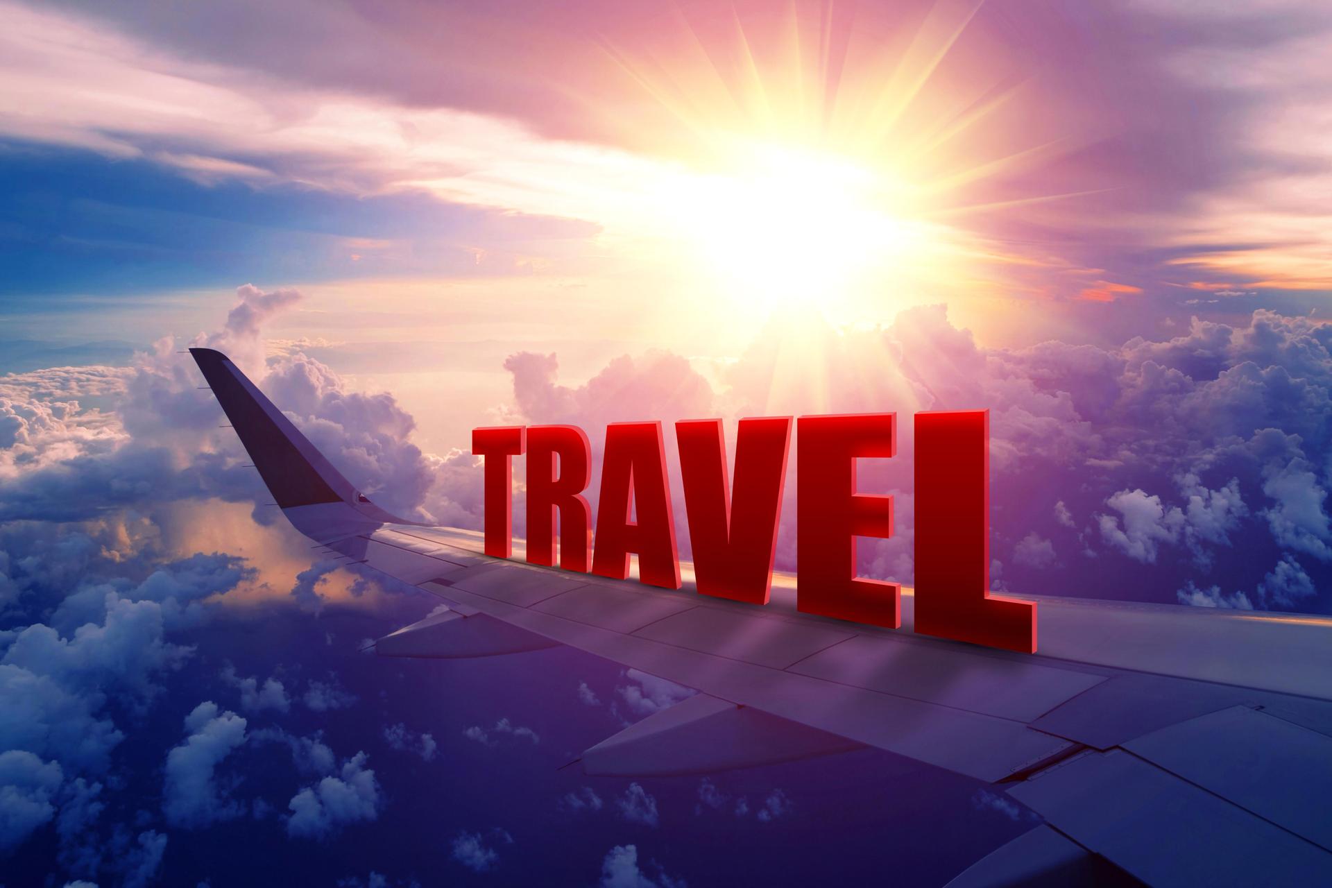 Airplane wing flying with "TRAVEL" at sunrise